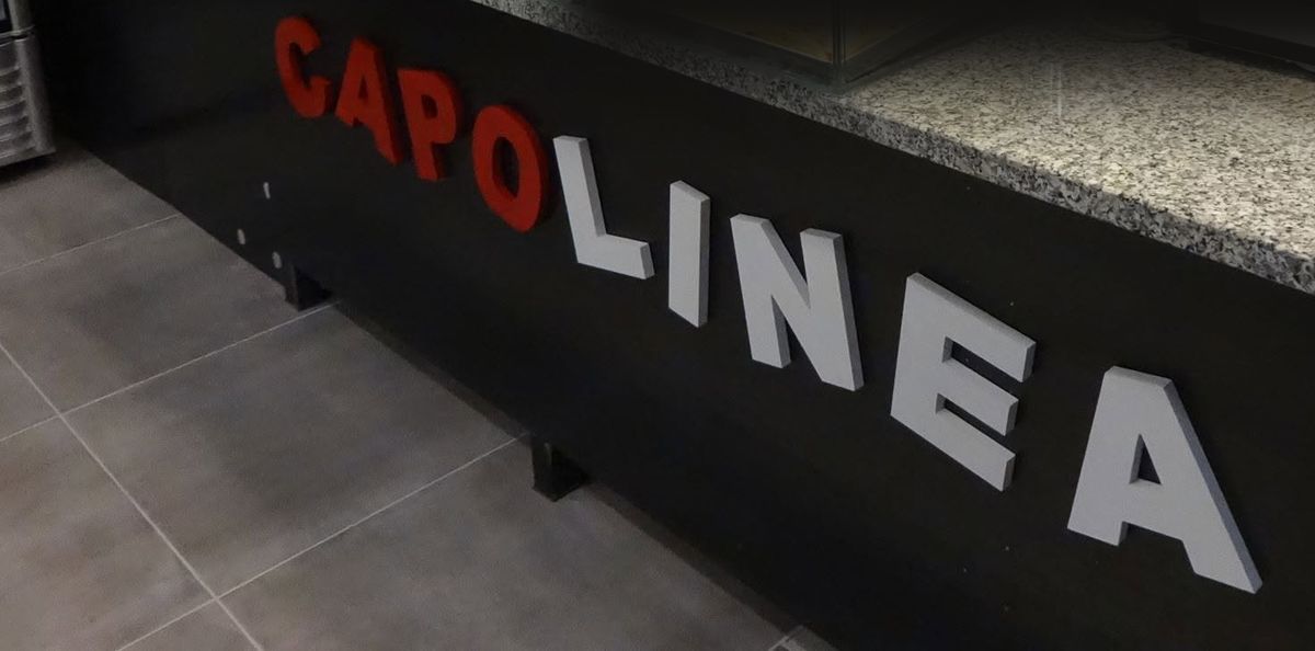 Il bancone del locale con la scritta CAPOLINEA in rosso e bianco
