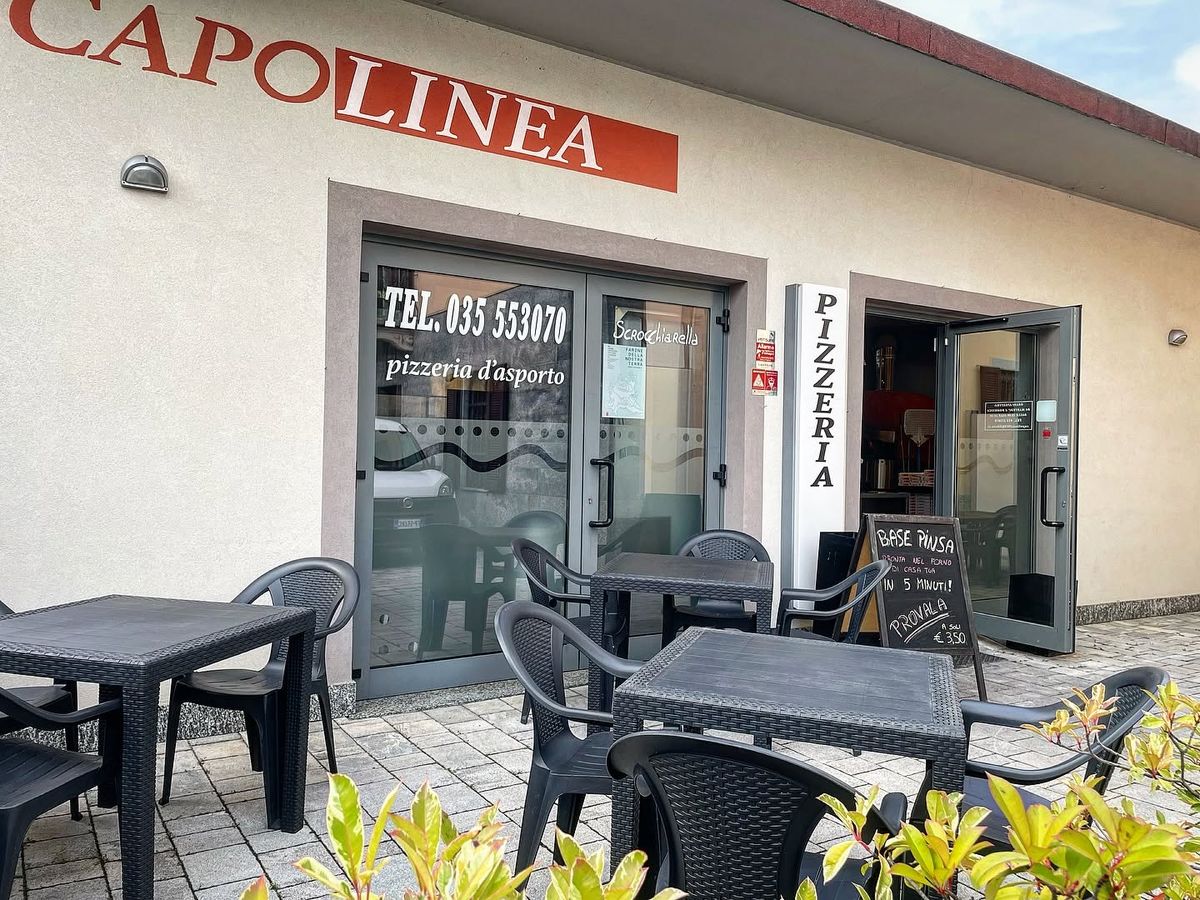 L'ingresso della pizzeria in Via Marconi 5, con l'insegna Capolinea e i tavolini fuori